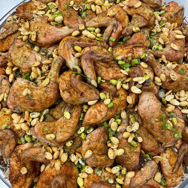 Close-up of Lebanese roasted chicken pieces with almonds, pistachios, and green onions.