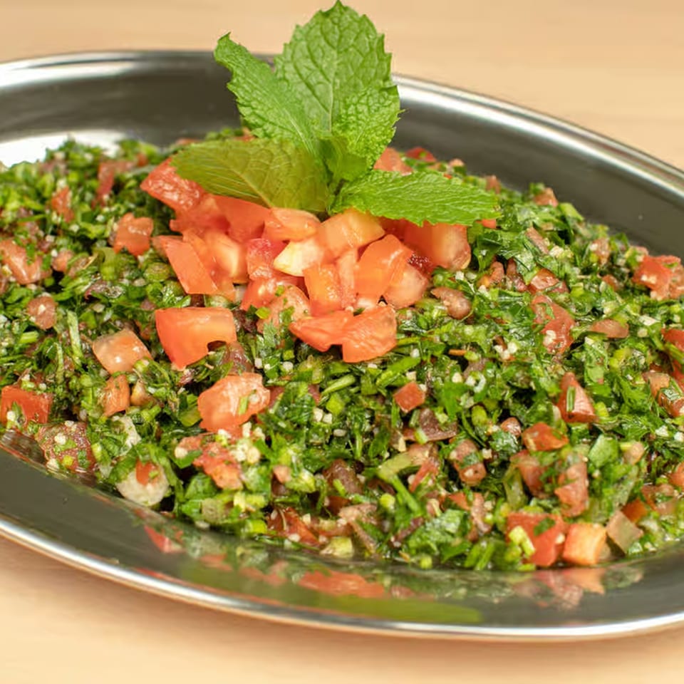 A close-up of a vibrant Lebanese tabbouleh salad with fresh parsley, tomatoes, and mint.