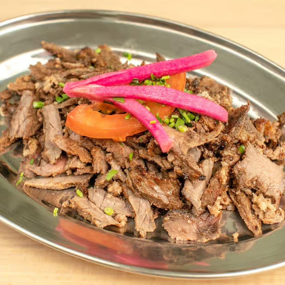 Shwarmas' Lebanese beef shawarma with pickled radishes, tomatoes, and chives on a silver platter.
