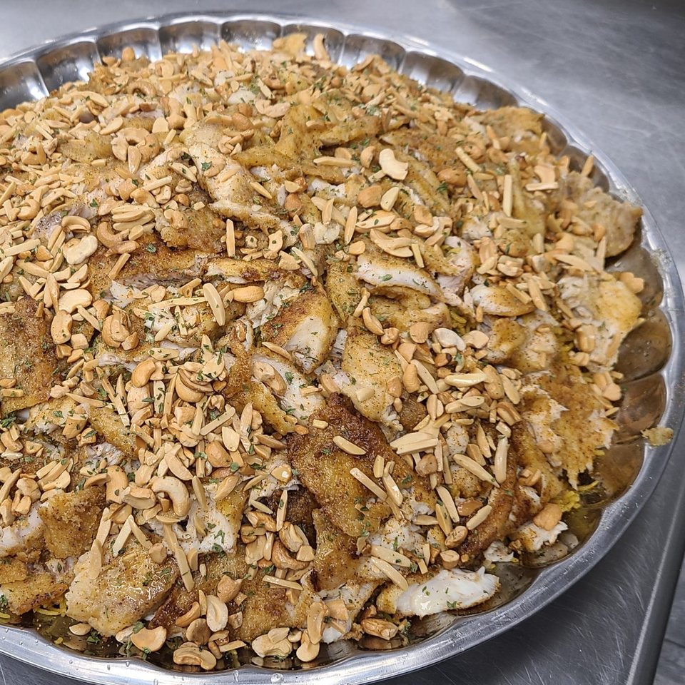 Lebanese Sayadieh, a large platter of spiced fish and rice topped with toasted nuts.