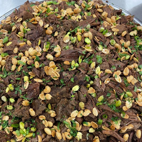Close-up of Lebanese shredded beef topped with toasted almonds, pistachios, and fresh herbs.