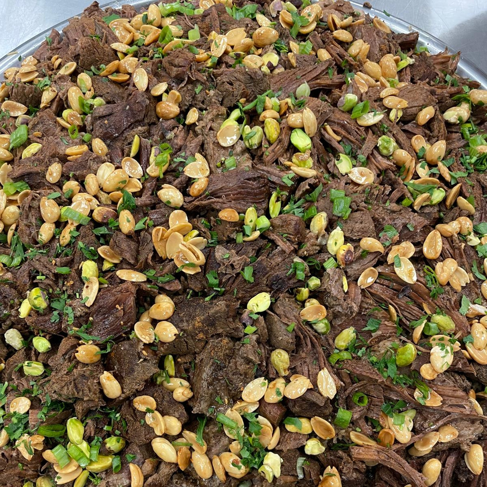 Close-up of Lebanese shredded beef topped with toasted almonds, pistachios, and fresh herbs.