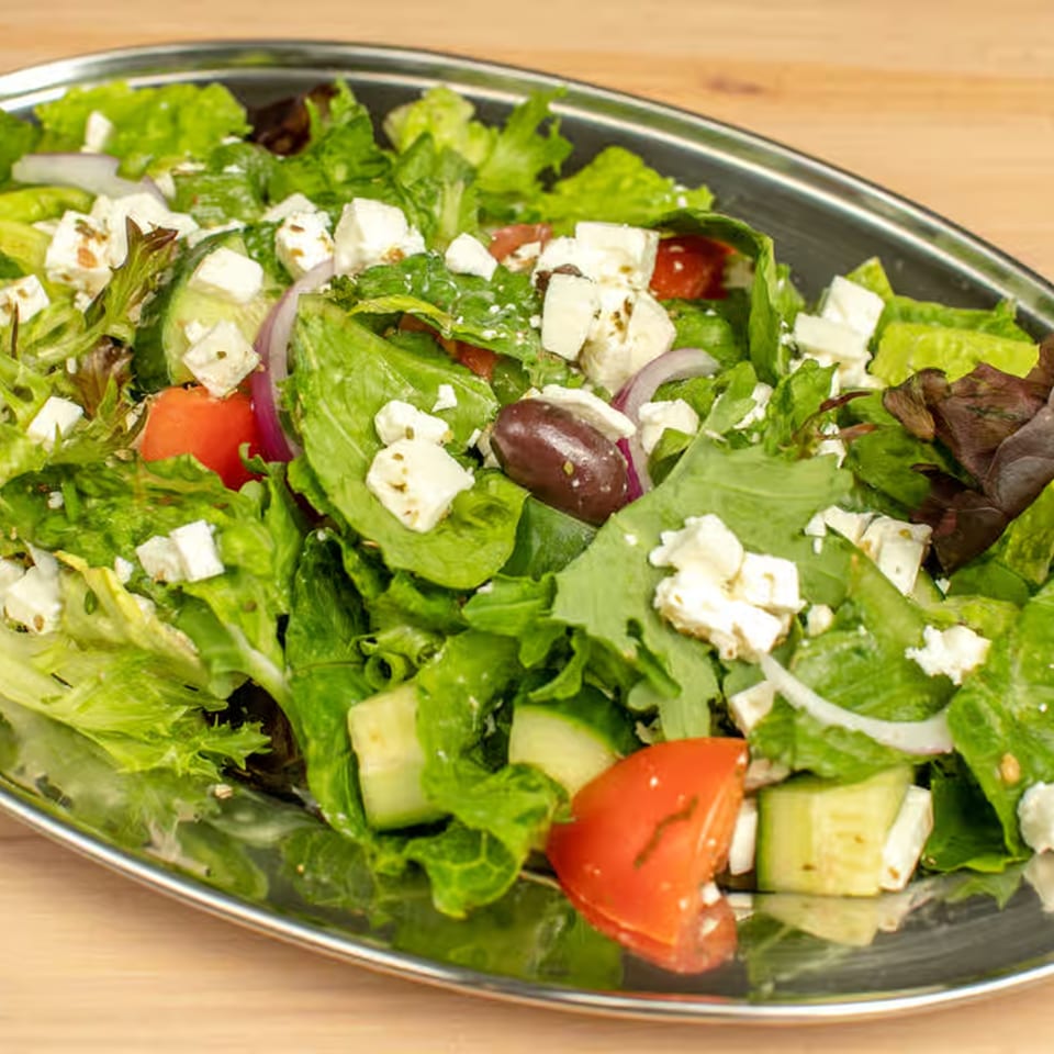 A vibrant Lebanese salad with mixed greens, tomatoes, cucumbers, red onion, feta, and olives.