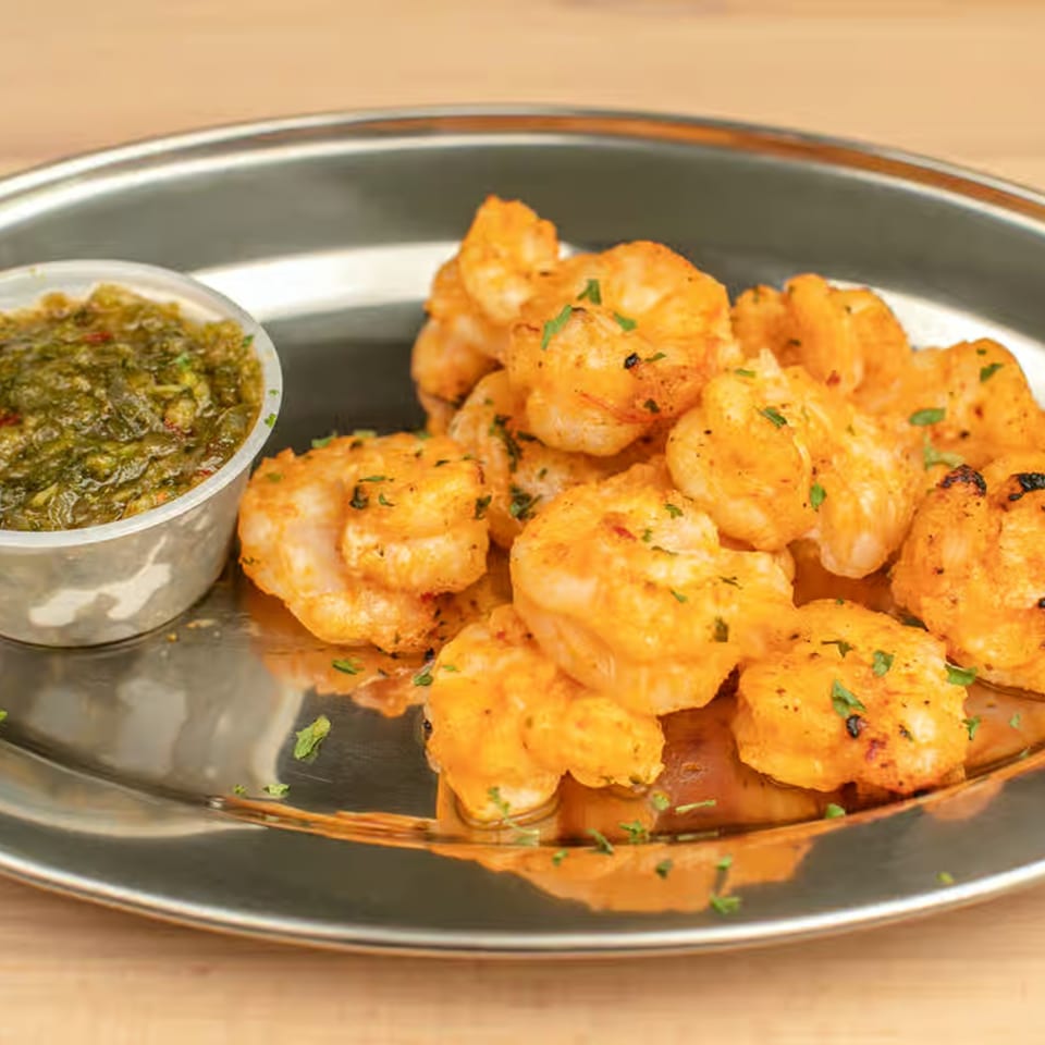 Lebanese-style grilled shrimp with green herb sauce on a silver platter.